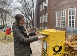(K)ein Weihnachten allein in Hamburg Die Redakteurin Julia schmeißt eine Postkarte in einen Briefkasten.