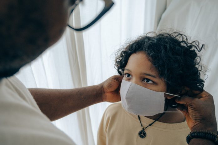 Ein Arzt zieht einem Kind eine Maske auf. RSV Virus belastet Hamburger Kinderkliniken.