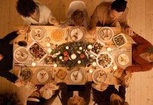 Weihnachtsessen: Braten, Fisch oder was ganz anderes? Eine Gruppe von Menschen sitzt an einem voll gedekcten Tisch mit Weihnachtsessen.