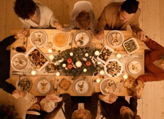 Weihnachtsessen: Braten, Fisch oder was ganz anderes? Eine Gruppe von Menschen sitzt an einem voll gedekcten Tisch mit Weihnachtsessen.