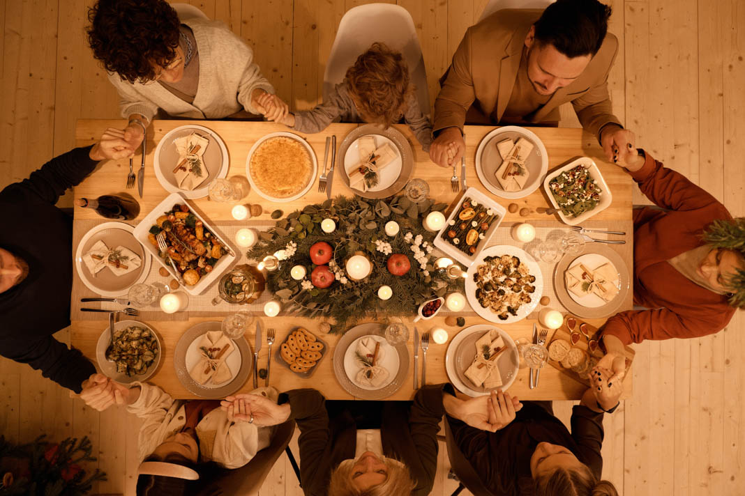 Eine Gruppe von Menschen sitzt an einem voll gedekcten Tisch mit Weihnachtsessen.