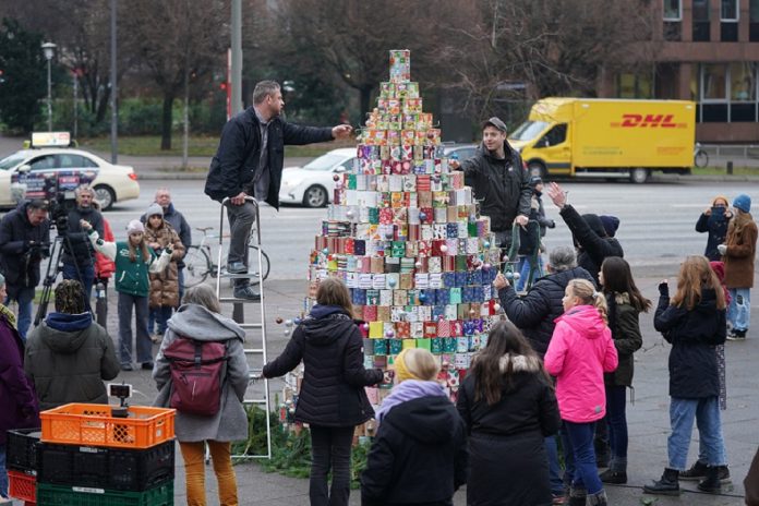 Helfer schmücken den größten Weihnachtsbaum aus Konservendosen auf dem Kirchplatz vor der Hamburger Hauptkirche Sankt Michaelis (Michel).