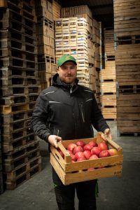 Jannis Schröder mit einer Kiste Äpfel in den Händen