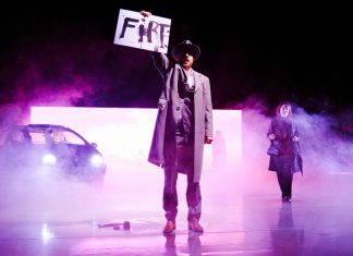 Rezension: „Barocco“ – ein Spiel mit dem Feuer Umgeben von Nebelschwaden steht Odin Biron für die Inszenierung „Barocco” auf der Bühne. Demonstrativ hält er ein Plakat in die Luft auf dem „Fire“ steht.