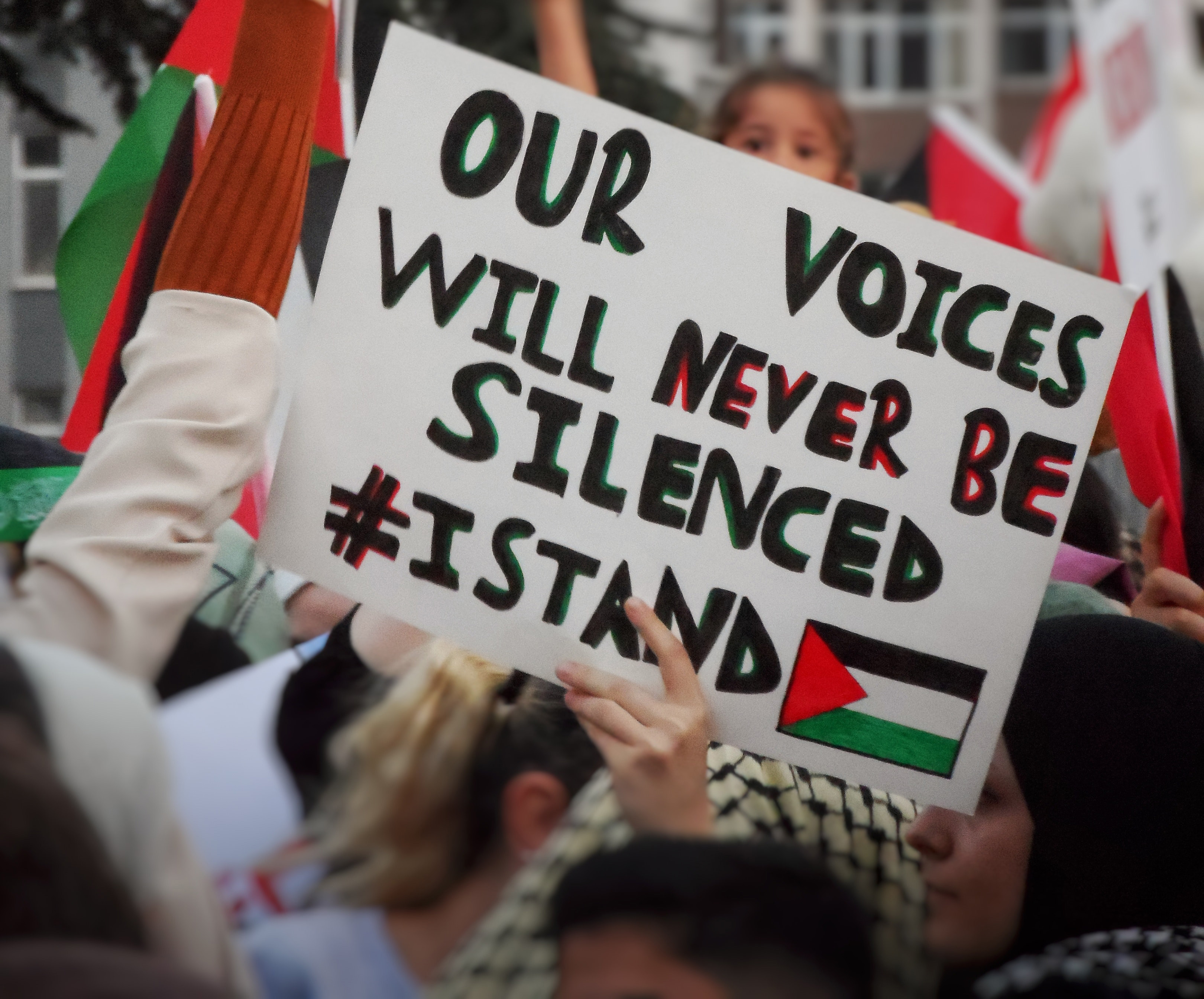 Auf einer pro-palästinensischen Demo hält eine Person ein Schild in die Höhe, auf dem "Our voices will never be silenced" steht. Foto: Seyma D.