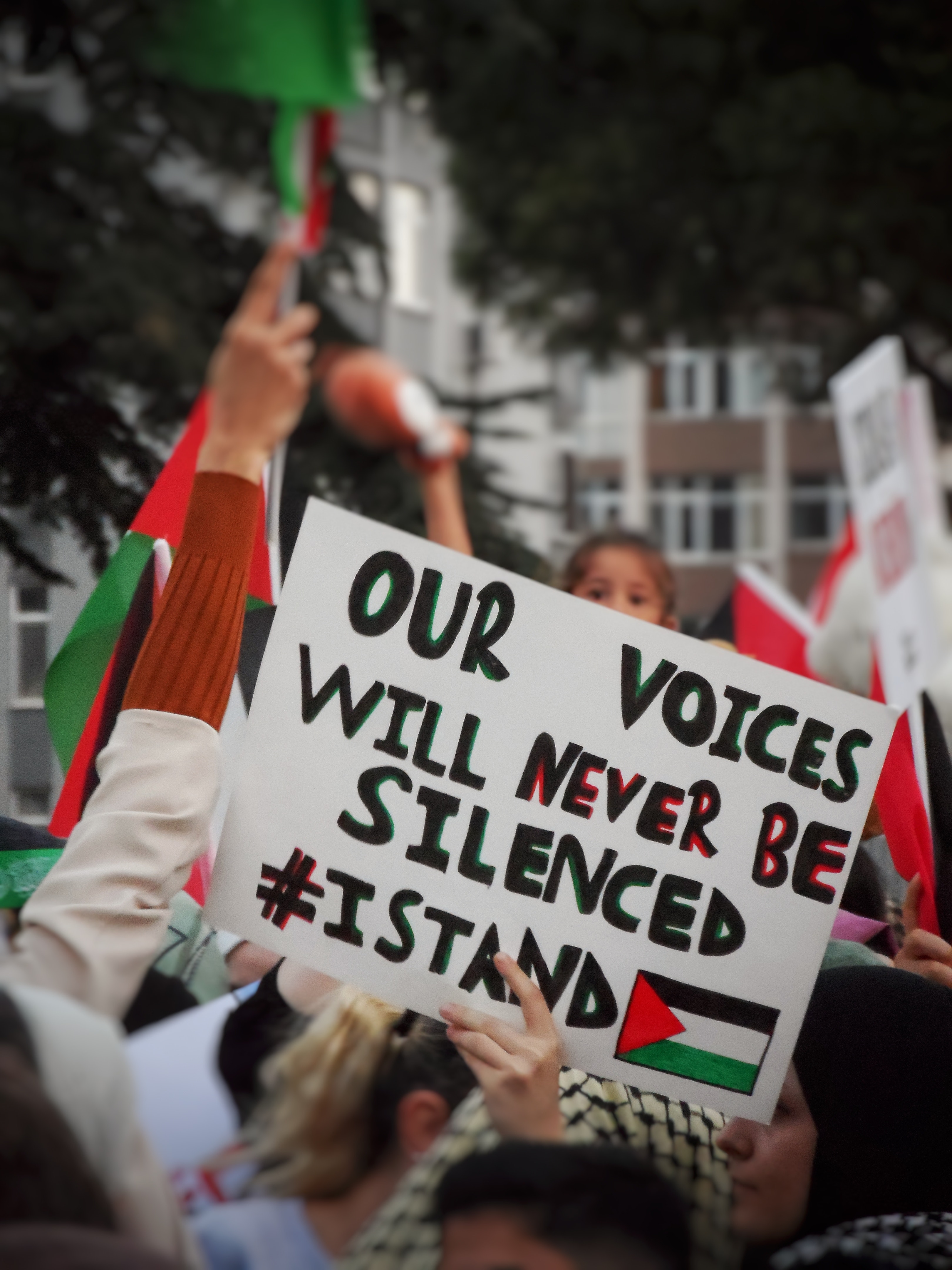 Auf einer pro-palästinensischen Demo hält eine Person ein Schild in die Höhe, auf dem "Our voices will never be silenced" steht. Foto: Seyma D.