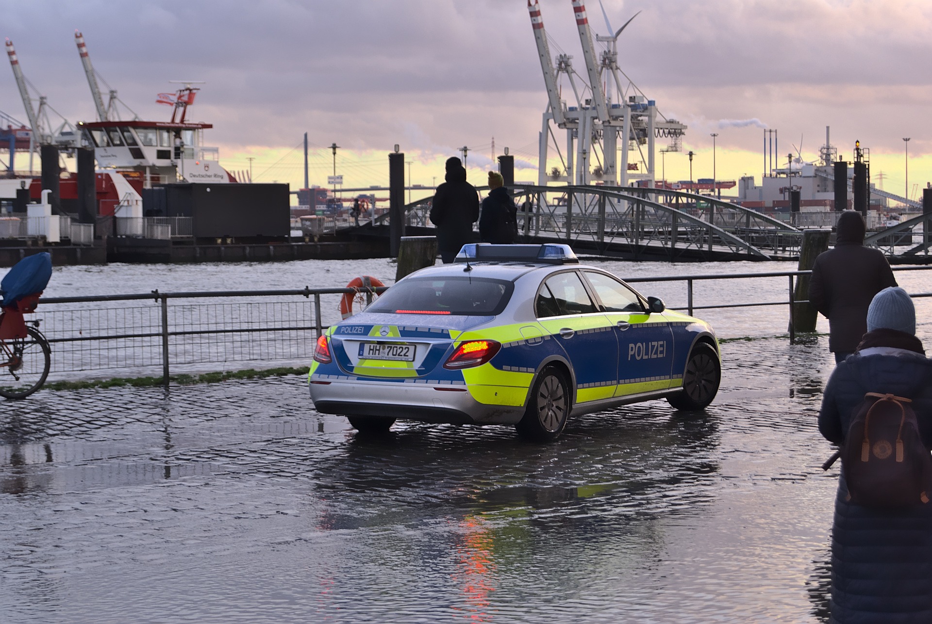 Ein Polizeiauto steht auf einem vom Hochwasser erfassten Uferweg.