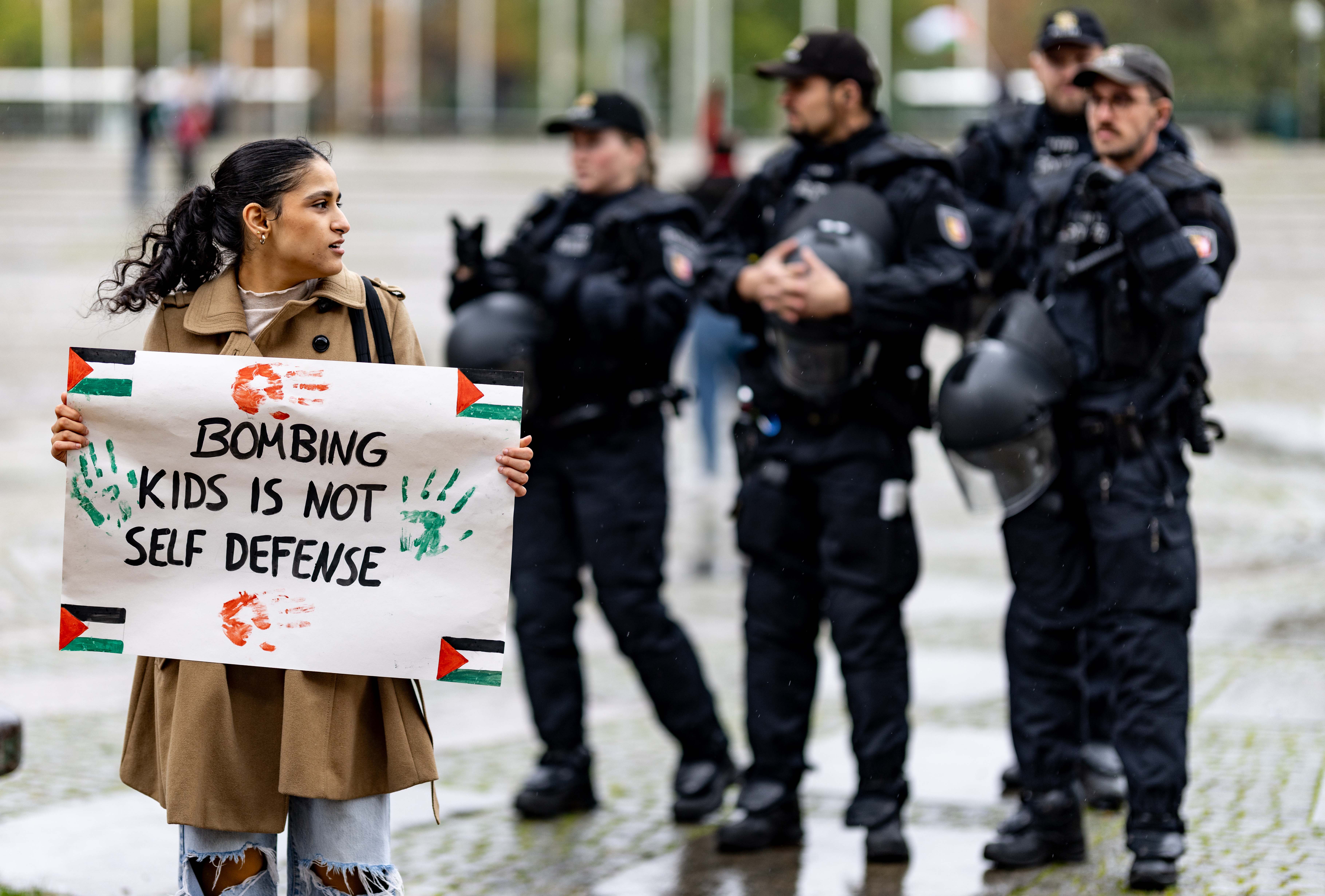 Eine junge Frau trägt ein Plakat mit palästinensischer und Flagge und Text.