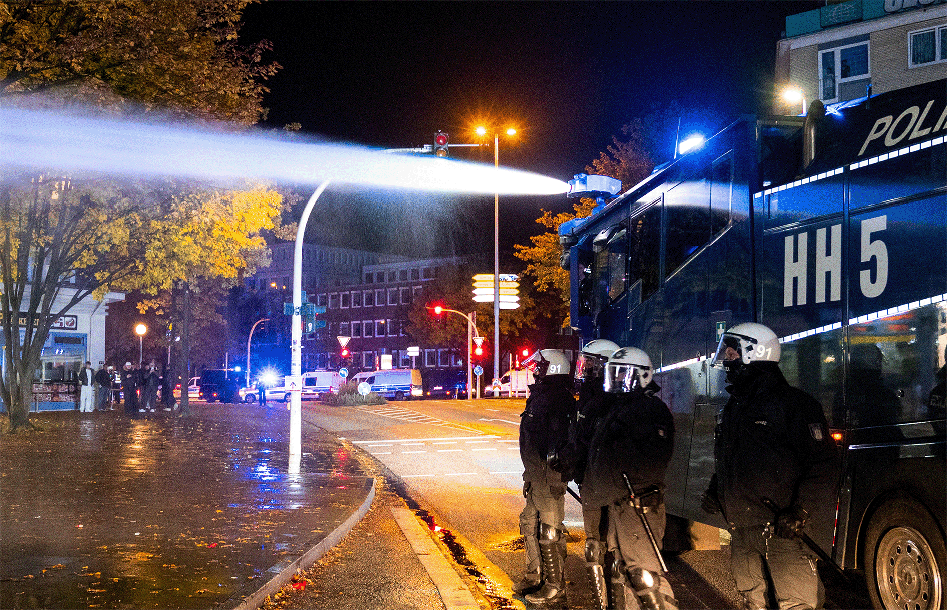 Hambuger Polizei steht vor einem Wasserwerfer auf einer Straße in Harburg.