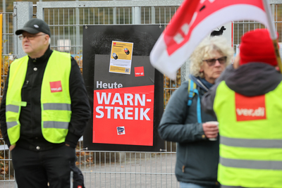 Streikende Arbeitskräfte stehen mit Warnwesten und Flaggen von ver.di.