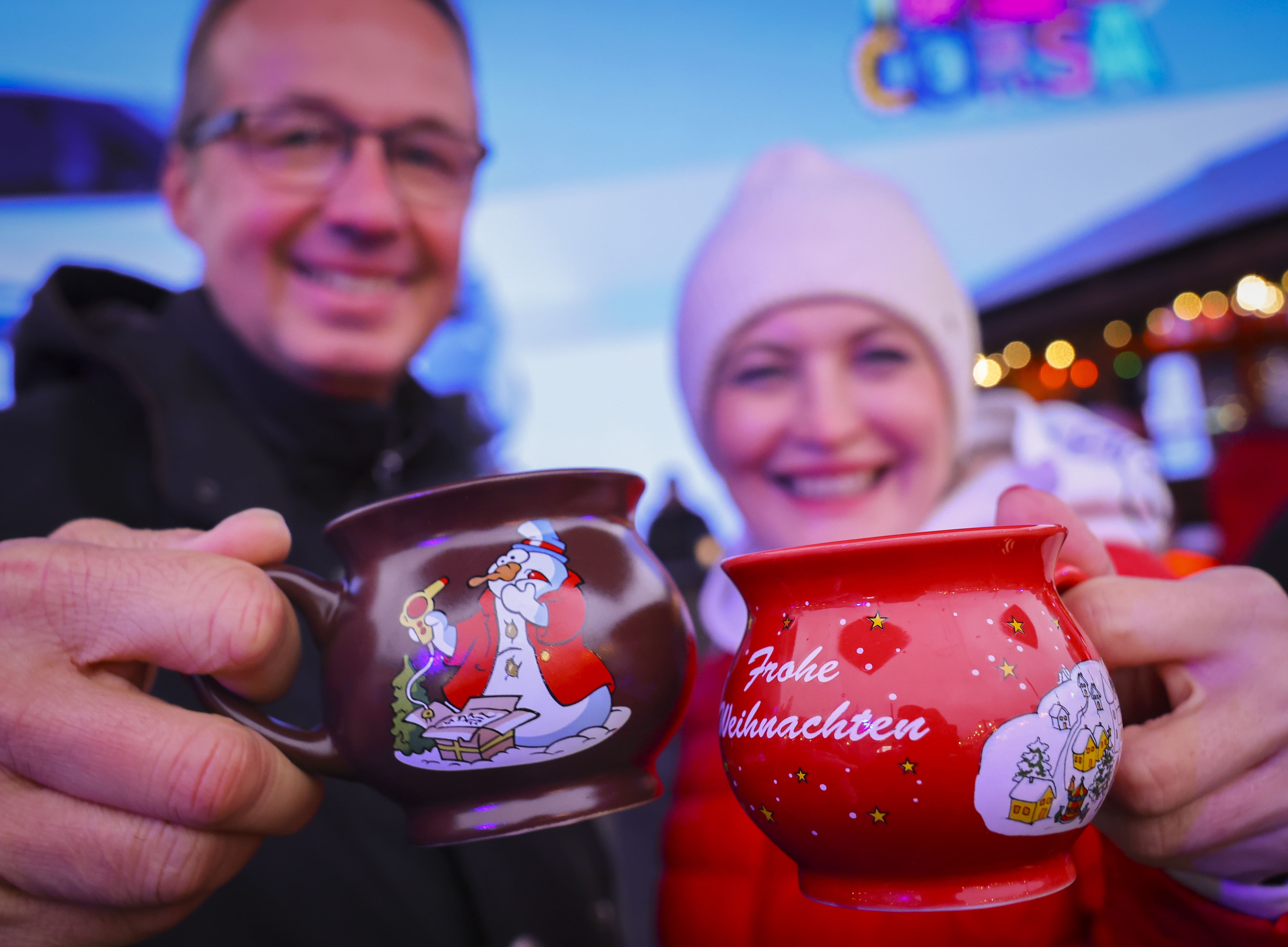 Ein Paar hält zwei Tassen mit heißem Glühwein kurz nach der Eröffnung des "Santa Pauli" in die Kamera.