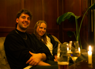 Willow Parlo: Dreamy Indie Pop zum Abheben Noemie und Jan von der Band Willow Parlo auf einem Sofa, vor ihnen stehen Gläser und eine Kerze