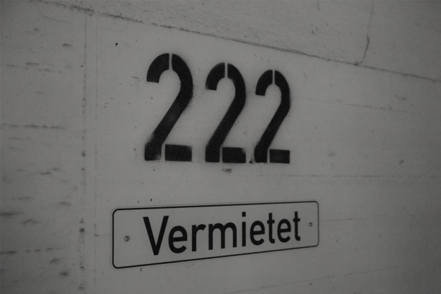 Weiße Wand mit der Aufschrift 222 und dadrunter auf einer Plakette das Wort Vermietet