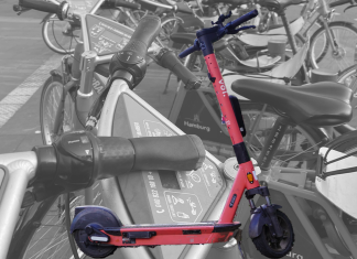Stehen statt treten: E-Scooter sind beliebter als Stadträder Fotocollage: Im Hintergrund Leihfahrräder, die auf einem Haufen auf einer Straße in Hamburg stehen in schwarz weiß. Im Vordergrund und in Farbe ein E-Scooter, der die Räder überstrahlt.