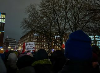 „Hamburg steht auf“: Demo am Freitag auf dem Rathausmarkt Von hinten sind Demonstrierende zu sehen. Auf einem Schild steht: Rassismus ist keine Alternative. Das Foto wurde bei einer vergangenen Demo gegen Rechts in Hamburg aufgenommen.