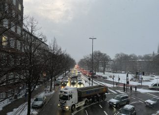 Glatte Straßen und Minusgrade in der Nacht zum Donnerstag Das Bild zeigt eine Kreuzung mit vielen Autos und einem LKW. Die Bürgersteige und Grünflächen sind voller Schnee.