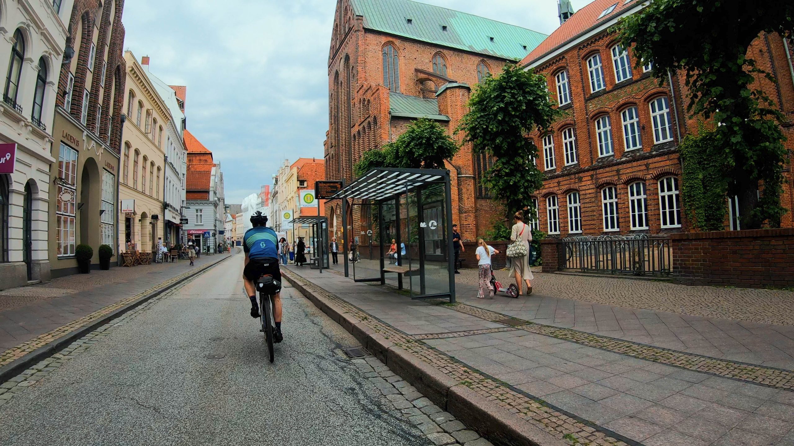 Ein Fahrradfahrer fährt durch die Lübecker Altstadt. Links und rechts historische Backsteingebäude.