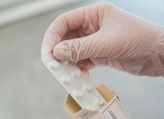 Bereicherung durch Corona-Medikament wohl auch in Hamburg Symbolbild Corona-Medikament Paxlovid: Eine Hand in durchsichtigem Handschuh zieht einen Pillenblister aus einer Medikamentenverpackung.
