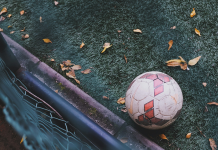 Baller League: Das musst du über die neue Fußballiga wissen Ein Fußball liegt auf dem Boden vom einem Kunstrasenfußballplatz. Ein paar braune BLätter von einem baum liegen auf dem Boden, um den Ball herum und ein Geländer ist zu sehen. Das Bild ist aus der Vogelperspektive aufgenommen.