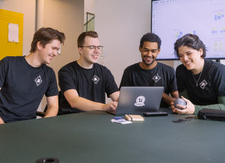 Wie wird man eigentlich Videospielentwickler? Vier Videospielentwickler, vor einem Laptop. Foto: Amberdive Interactive