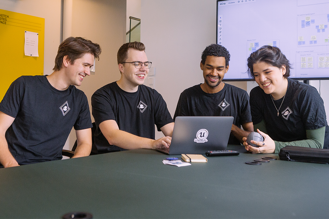 Vier Videospielentwickler, vor einem Laptop. Foto: Amberdive Interactive