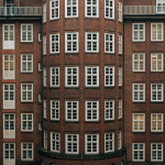 Ein Jahr Wohngeld-Plus: Doppelt so viel Geld und Empfänger Rotes Backsteingebäude von außen, in der Mitte eine Rundung, viele Fenster