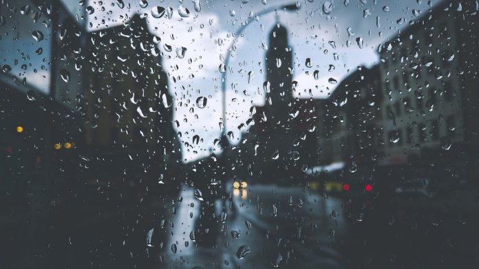 Blick durch Regentropfen an einer Scheibe auf eine Stadt.