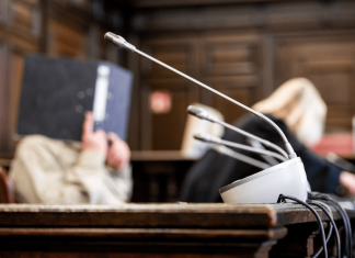 Reichsbürger-Prozess: Die bizarren Pläne der „Kaiserreichsgruppe“ Der Angeklagter der Kaiserreichsgruppe sitzt im Verhandlungssaal und verbirgt sein Gesicht hinter einem Ordner.