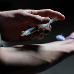 Weniger Drogentote in Hamburg Ein Mann hält eine Heroinspritze an seinen Arm. Foto: Frank Leonhardt/dpa