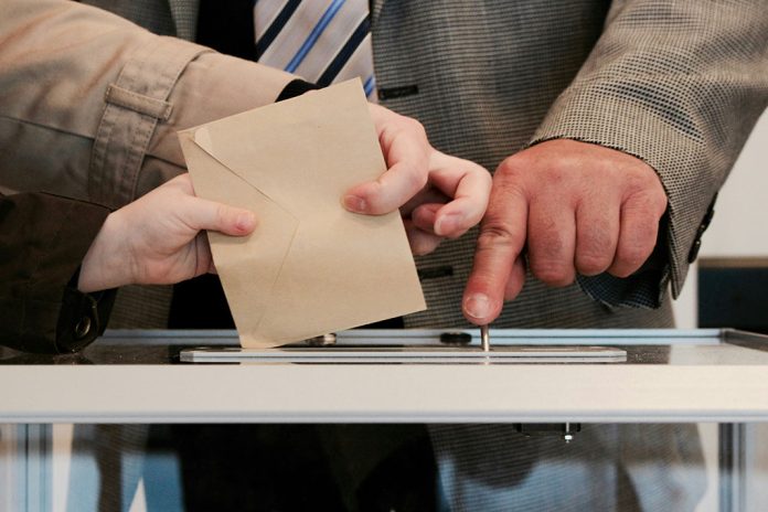 Wahlen Hamburg: Stimmzettel wird in Urne geworfen.