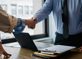 Höchststand von neu gegründeten Unternehmen Zwei Menschen reichen sich über den Schreibtisch hinweg die Hand