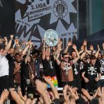 „Scheiß aufs Wetter, wir machen weiter” Aufstiegsfeier FC St. Pauli. Jackson Irvine (mit Meisterschale) und die Mannschaft feiert auf der Bühne auf dem Spielbudenplatz auf der Reeperbahn