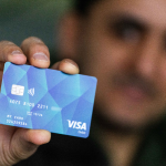 Über 1100 Bezahlkarten an Asylbewerber*innen verteilt Ein Mann hält eine der neuen Bezahlkarten in die Kamera.