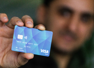 Über 1100 Bezahlkarten an Asylbewerber*innen verteilt Ein Mann hält eine der neuen Bezahlkarten in die Kamera.