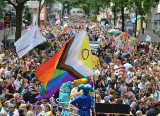 CSD Hamburg: Die Veranstaltungen im Überblick Menschenmassen ziehen durch Hamburg. In der Mitte schwenkt jemand eine Pride-Flagge.