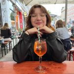 Sarah auf der Schanue mit einem Glas Aperol vor sich. 