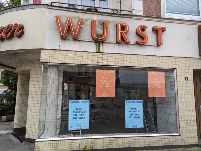 Die Ladenfront einer ehemaligen Fleischerei in Eimsbüttel. In den Fenstern hängen Plakate für ein Yogastudio, das mittlerweile seinen Platz eingenommen hat.