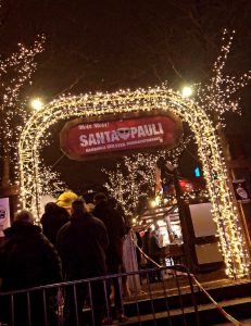 Eine Gruppe von Menschen steht vor dem Eingangstor des Weihnachtsmarkts Santa Pauli. Foto: Lara Kitzinger