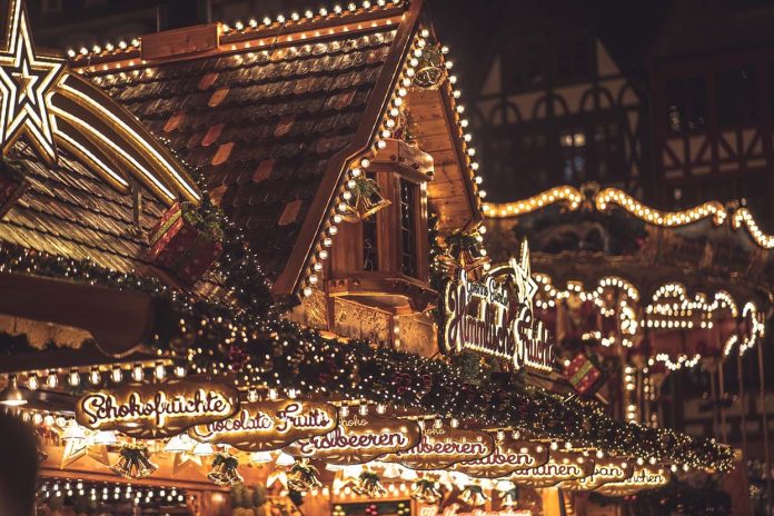 Weihnachtsmarktbude im Dunkeln mit vielen Lichtern.