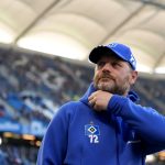 Erneuter Umbruch beim HSV Der ehemalige HSV-Trainer Steffen Baumgart trägt eine Cap und eine Jacke mit dem HSV-Logo. Er steht in einem Fußballstadion.