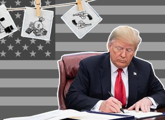 Trump is back: Was sind seine Pläne? Trump sitzt am Schreibtisch. Im Hintergrund ist die US-Flagge zu sehen.