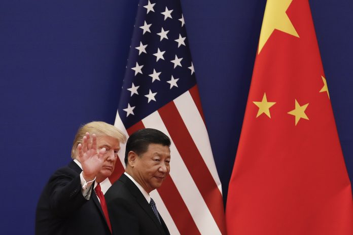 Donald Trump und Xi Jinping vor einer chinesischen und einer US-Flagge. Trump winkt in die Kamera.