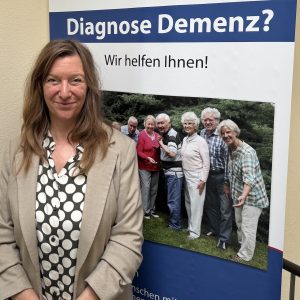 Johanna Grünhagen von der Alzheimer Gesellschaft in Hamburg steht vor einem Plakat. 