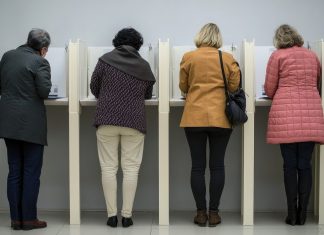 Wie gefährlich sind KI-Fakes im Wahlkampf? Vier Menschen stehen nebeneinander in Wahlkabinen.