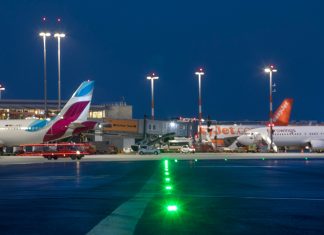 Hamburger Flughafen erwartet Hochbetrieb Ein Bild vom Flughafen Hamburg im Dunkeln. Man sieht verschiedene Flugzeuge, die auf dem Rollfeld stehen und bunte Lichter leuchten.