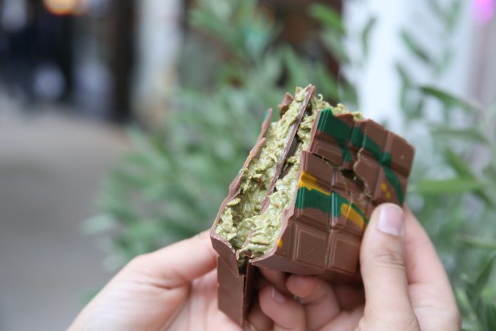 Zwei Hände halten eine in der Mitte gebrochene Tafel Dubaischokolade in die Kamera.