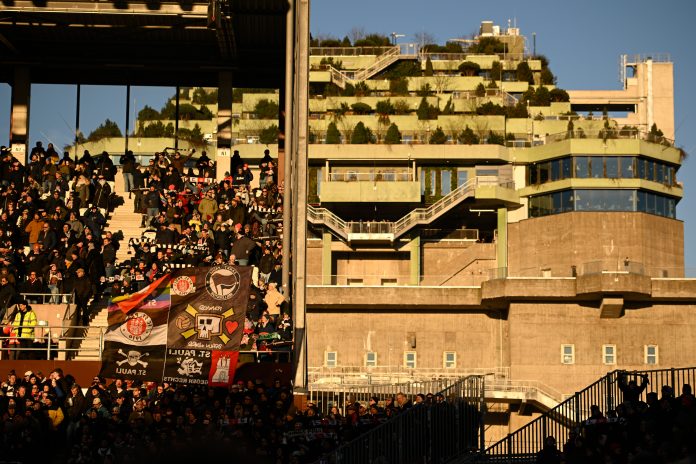 Fans des FC St. Pauli auf der Tribüne des Millerntor Stadions. Im Hintergrund der Bunker auf dem Heiligengeistfeld.