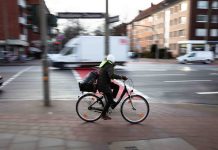 Symbolbild für Radfahren in Hamburg. Ein Radfahrer auf einer Straße, der Hintergrund ist verschwommen.