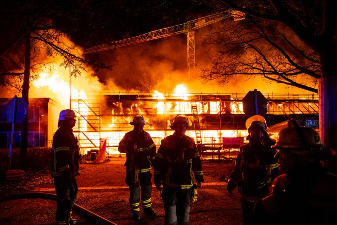 Hamburg: Feuerwehrleute löschen im Stadtteil Lohbrügge einen brennenden Neubau von einer Schule. Der Großbrand auf dem Schulgelände beschäftigt am Abend die Feuerwehr, starker Wind facht die Flammen zusätzlich an.