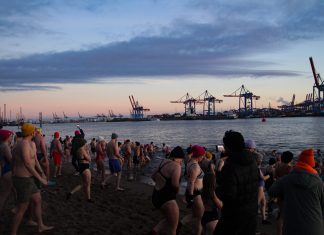 Kaltes Wasser, warme Herzen: Eisbaden in der Elbe Eine große Gruppe an Menschen steht in Badekleidung am Elbstrand